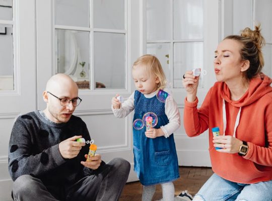 Family enjoying quality time blowing bubbles indoors, capturing joyful moments.