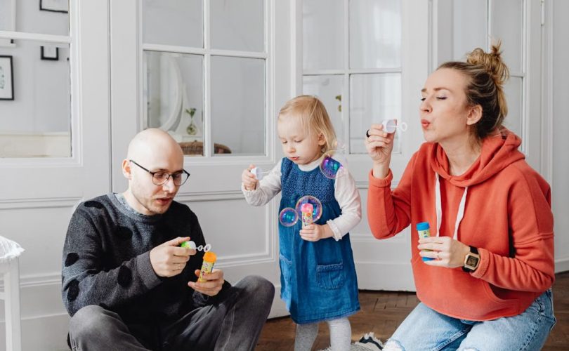 Family enjoying quality time blowing bubbles indoors, capturing joyful moments.